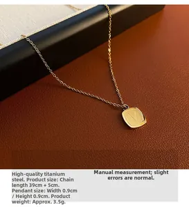Detail of V-engraved gold square pendant on titanium steel chain over leather