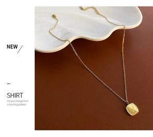 Detail of gold titanium steel necklace featuring a square V letter pendant for women