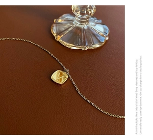Macro shot of gold V-letter square pendant necklace on premium brown leather backdrop