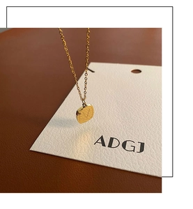 Macro detail of gold-plated square pendant with V-engraving and brushed metal texture