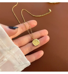 Macro shot of gold stainless steel square pendant with V engraving on a delicate chain