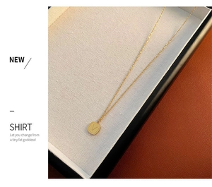 Close-up of golden square pendant with engraved letter V on elegant jewelry tray