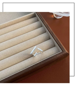 Minimalist silver geometric open ring displayed on a linen cushion in a wooden jewelry tray