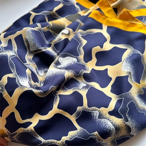 Détail d'un foulard en soie avec imprimé géométrique bleu marine et jaune et texture lisse