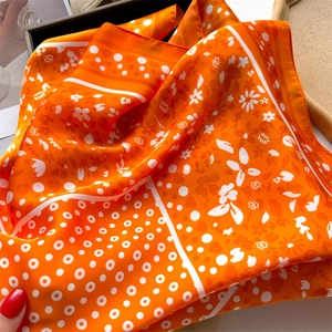 Close-up of orange satin scarf with daisy and heart patterns showing smooth texture