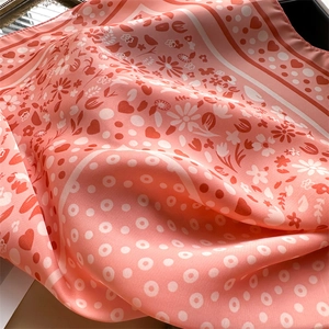 Detailed view of pink satin scarf with heart polka dots and smooth silky texture