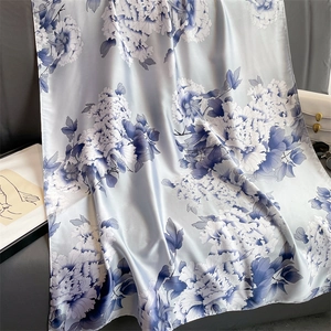 Elegant light blue silk shawl with large peony floral print on gray leather sofa