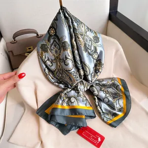 Écharpe élégante en soie synthétique avec motif Paisley bleu-gris sur un pull beige