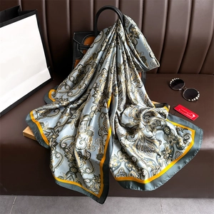 Détail d'un châle en soie à motif paisley bleu et jaune drapé sur un sac en cuir chic