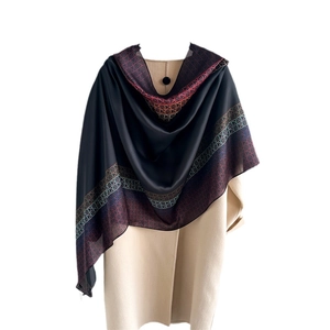 Sciarpa di lusso in seta con motivi geometrici colorati su un cappotto beige