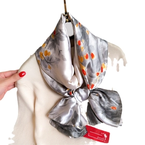 Elegant silver silk scarf with orange floral ink print on white turtleneck sweater