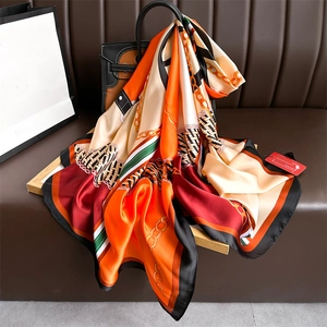 Detail of silk scarf with chain and harness patterns draped on a luxury leather handbag