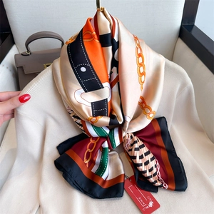 Large chain print silk scarf with colorful geometric patterns on a beige sweater