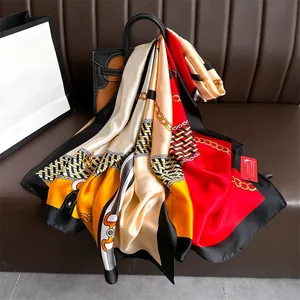 Detail of elegant chain print satin scarf draped over a brown leather handbag