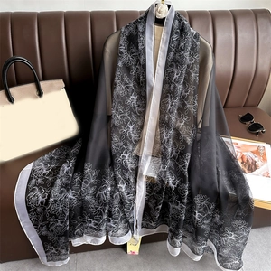 Élégante écharpe en soie à motif floral noir et blanc sur un canapé en cuir