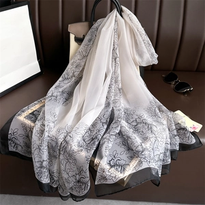 Gros plan d'un foulard en soie à motifs de pivoines noires drapé sur un sac à main