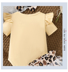 Infant yellow bodysuit with ruffle shoulders and leopard print pants on woven textile