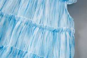 Gros plan sur les volants dégradés bleu et blanc avec coutures détaillées de la robe