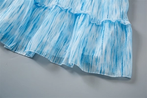 Détail des volants à rayures dégradées bleues sur une robe d'été légère pour fille