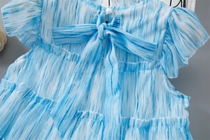 Détail du dos d'une robe en mousseline tie-dye bleue avec nœud et bouton perle