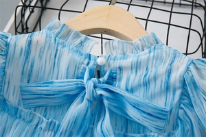 Détail d'encolure à volants pour filles avec bouton perle et nœud papillon bleu