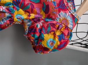 Detail of puffed sleeves with elastic cuffs on a rose red floral summer dress for girls