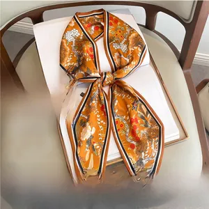Close-up of orange silk scarf with vintage floral patterns tied in a bow on a white book