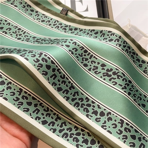 Dettaglio macro di un foulard in seta con strisce leopardate verdi e trama liscia