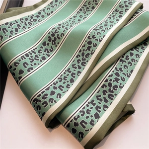 Dettaglio della sciarpa in seta verde con strisce beige e motivo leopardato nero fine