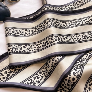 Dettaglio di sciarpa in seta a macchie e righe con occhiali da sole alla moda