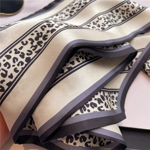 Dettaglio di un foulard sottile in raso con stampa leopardata e bordi a righe eleganti