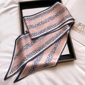 Dettaglio della sciarpa in seta leopardata rosa su tessuto bianco con trama elegante e luce