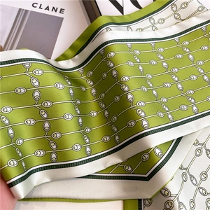 Elegant green silk neck scarf with geometric patterns shown in a stylish stack