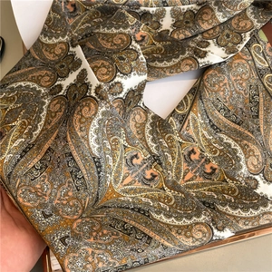 Detail of silk-like paisley scarf showing smooth texture and elegant brown pattern