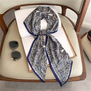 Detailed close-up of blue paisley silk scarf tied in a bow knot on a vintage book