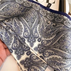 Detailed view of paisley silk scarf with blue and white pattern and smooth texture
