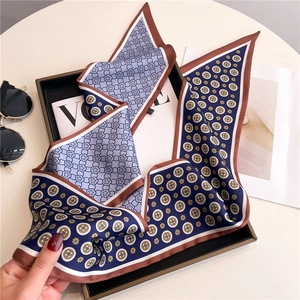 Chic long narrow silk-feel scarf with blue and brown vintage patterns on a sleek black tray