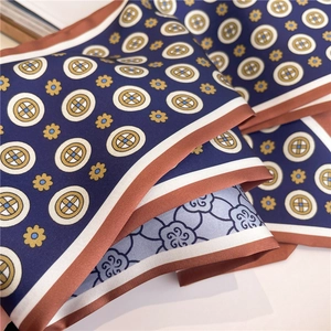 Macro detail of navy silk-like scarf with white ring patterns and elegant floral print