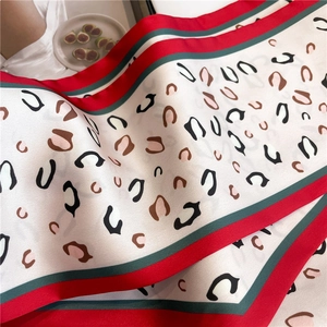 Detailed macro view of leopard print silk scarf with classic red and green striped border