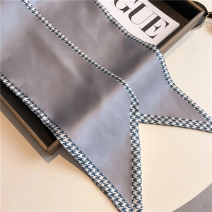Macro detail of silk scarf with blue houndstooth border on satin fabric texture