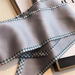 Detail of grey silk ribbon scarf with classic black and white houndstooth trim texture
