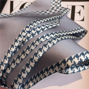 Close-up of gray satin skinny scarf with houndstooth trim on a fashion magazine