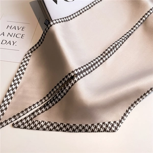 Detail of champagne satin skinny scarf with houndstooth borders and silky texture drape