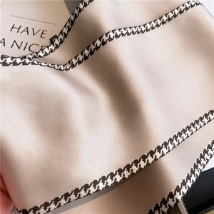 Detail of champagne satin scarf with houndstooth edge and smooth silky texture