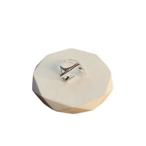Minimalist silver geometric overlap ring with modern architectural design on white stone