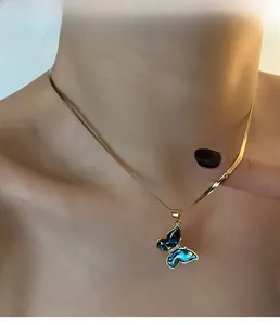 Macro shot of butterfly pendant with abalone shell inlay on golden flat snake chain