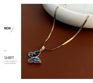 Detailed close-up of a butterfly pendant featuring iridescent abalone shell on a gold snake chain