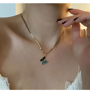 Macro view of gold snake chain with butterfly pendant and iridescent abalone shell inlay
