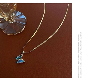Macro shot of butterfly abalone shell pendant on gold snake chain against leather