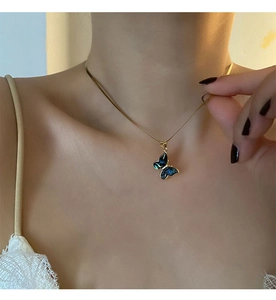 Detail of a butterfly abalone shell pendant on a gold snake chain worn by a model